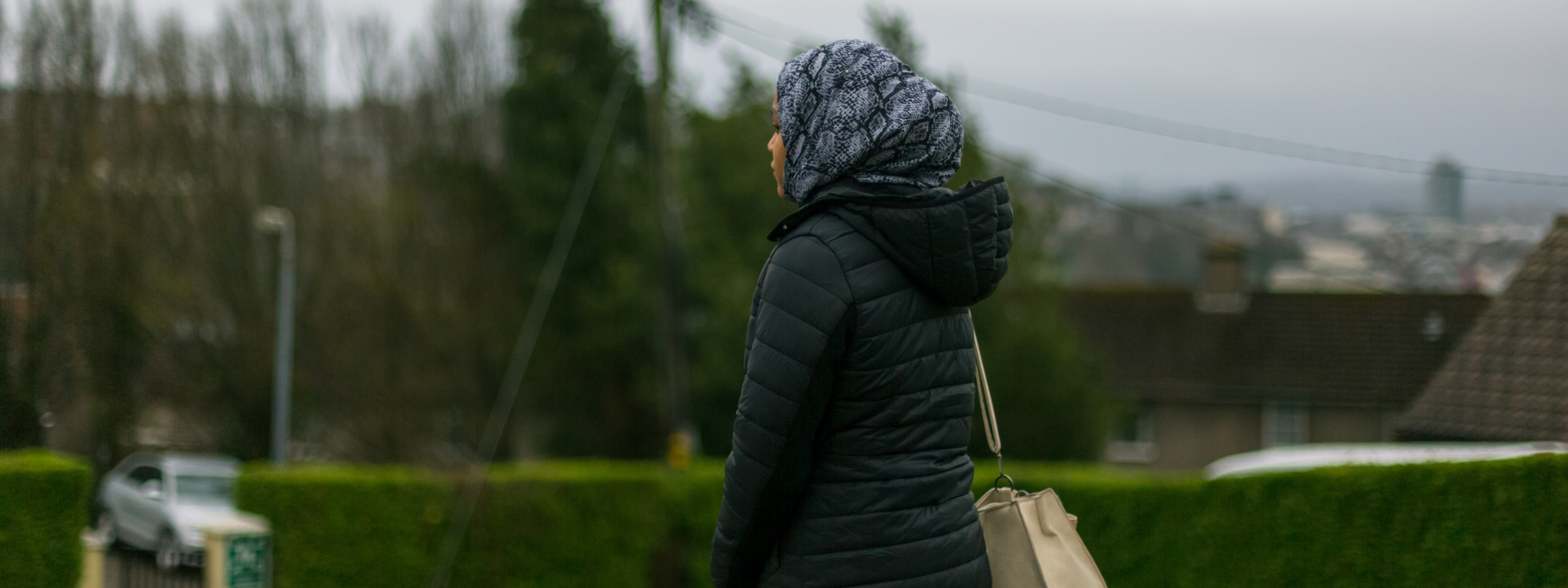 Young woman standing in a green area with her faced turned away from the camer