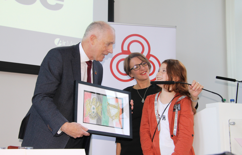 Young Syrian refugee presenting artwork to the Minister for Integration 